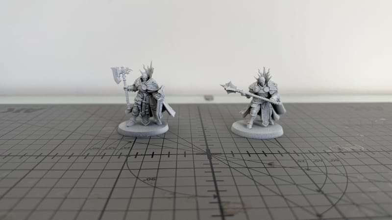 Two Reclusians, built and unpainted in grey plastic, standing on a cutting mat.