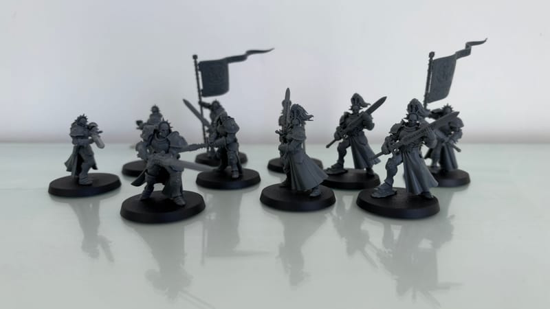 Ten built, unpainted Vanquishers standing together on a white table.